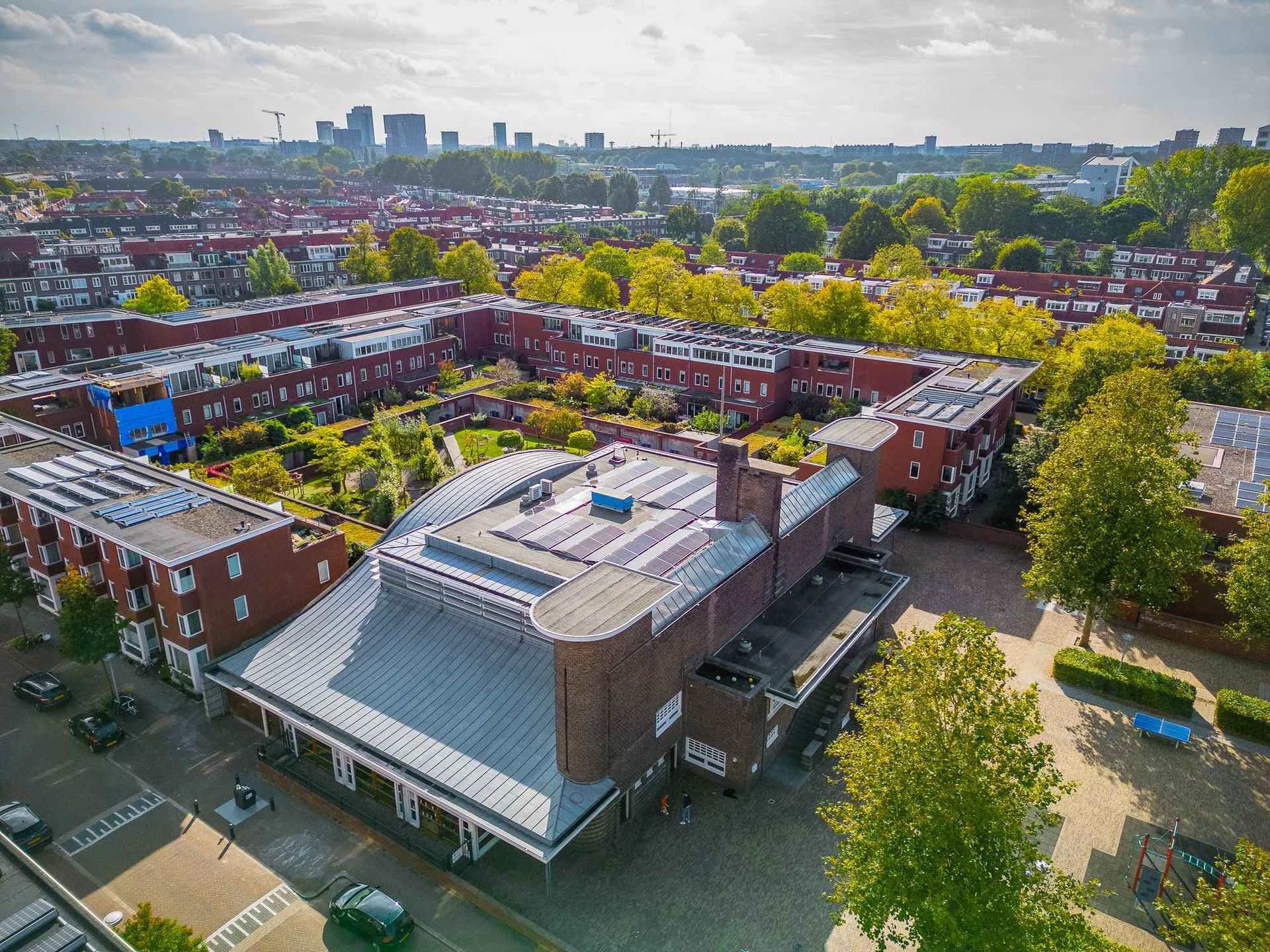 Een luchtfoto van een groot gebouw in een woonwijk met een stad op de achtergrond.