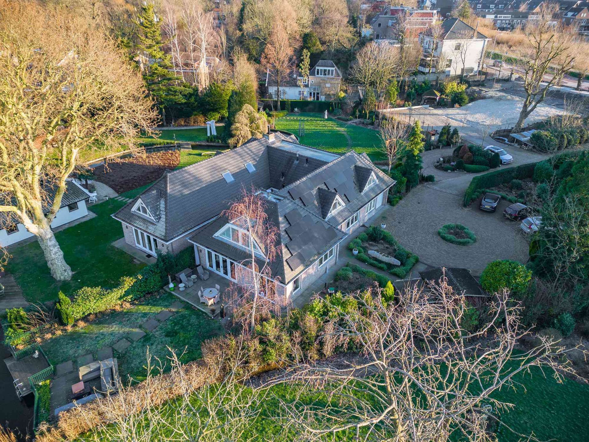 Een luchtfoto van een groot huis omgeven door bomen en gras.