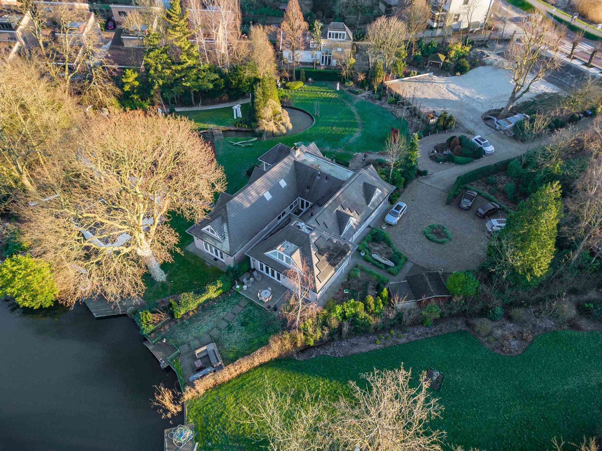 Een luchtfoto van een groot huis omgeven door bomen en een meer.