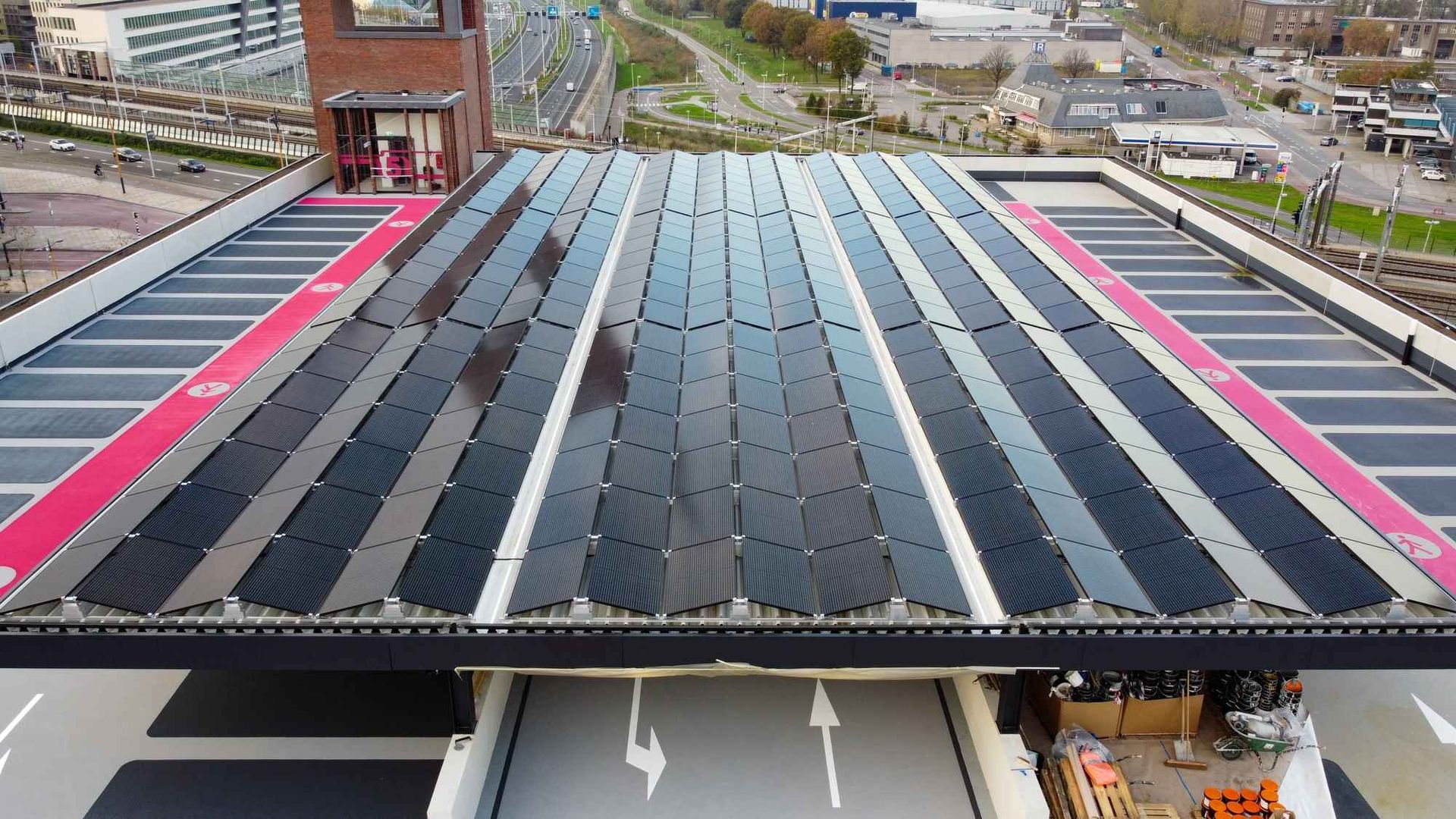 Een luchtfoto van een parkeergarage met zonnepanelen op het dak