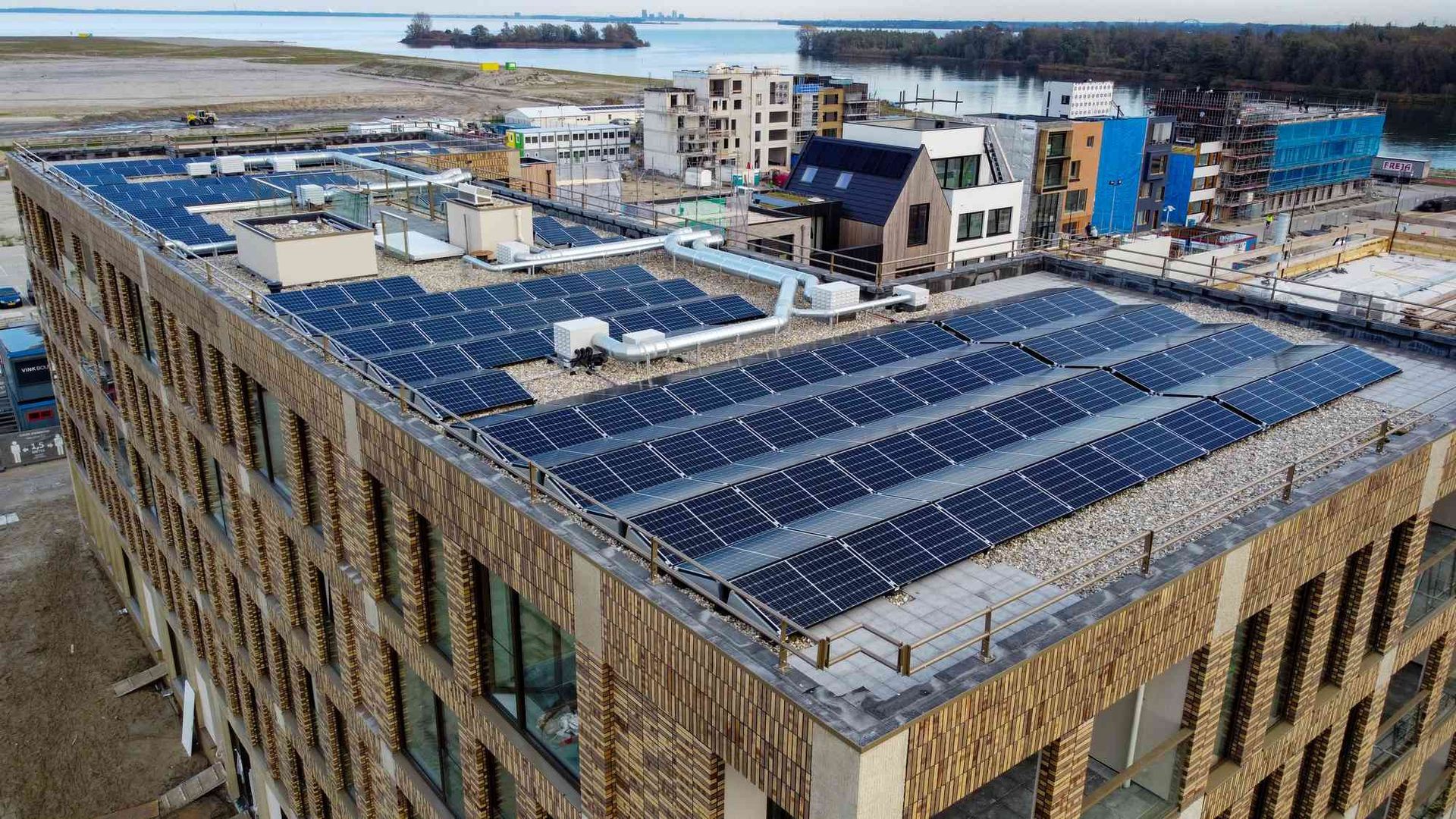Een groot gebouw met veel zonnepanelen op het dak.