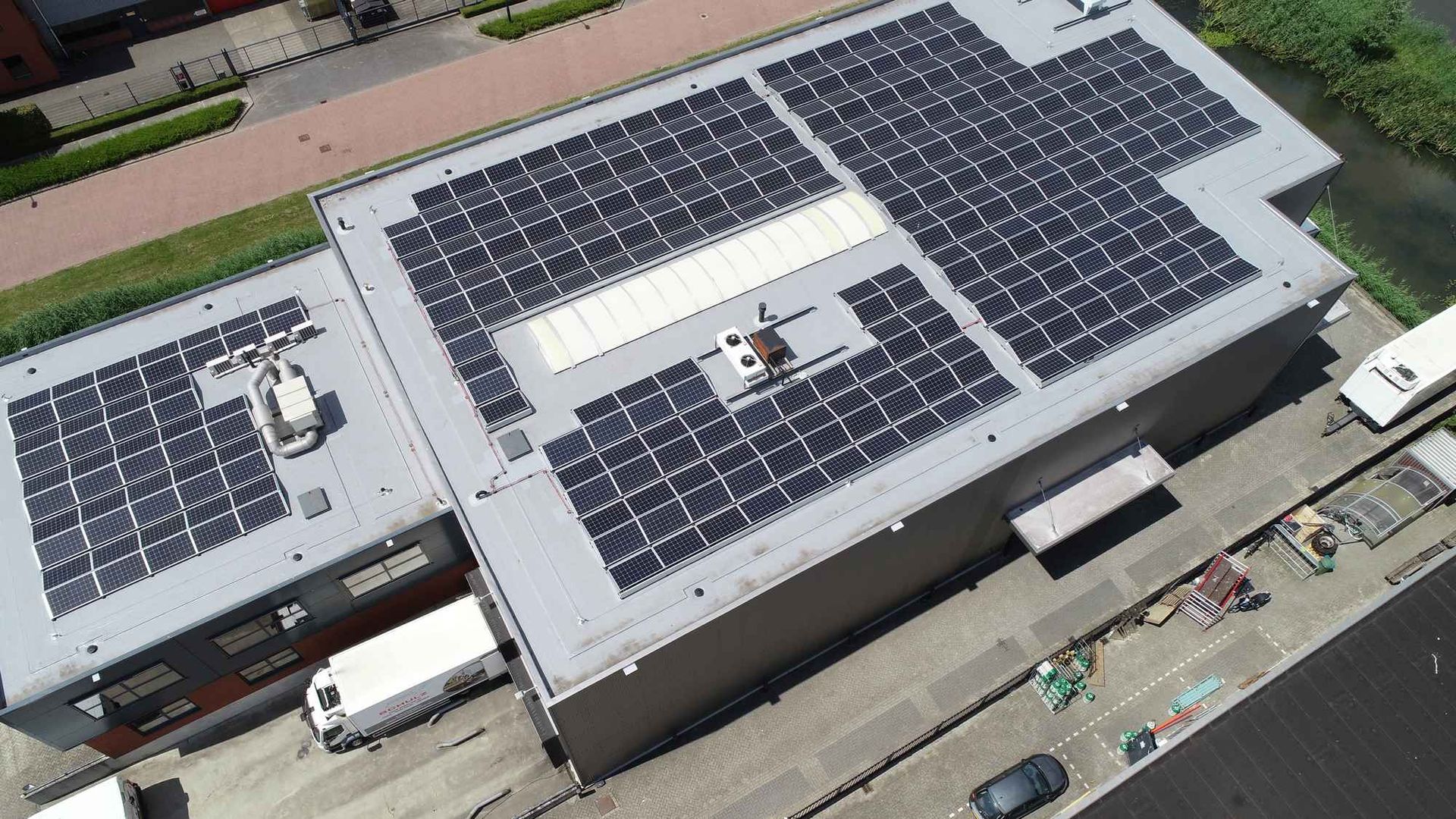 Een luchtfoto van een gebouw met veel zonnepanelen op het dak.