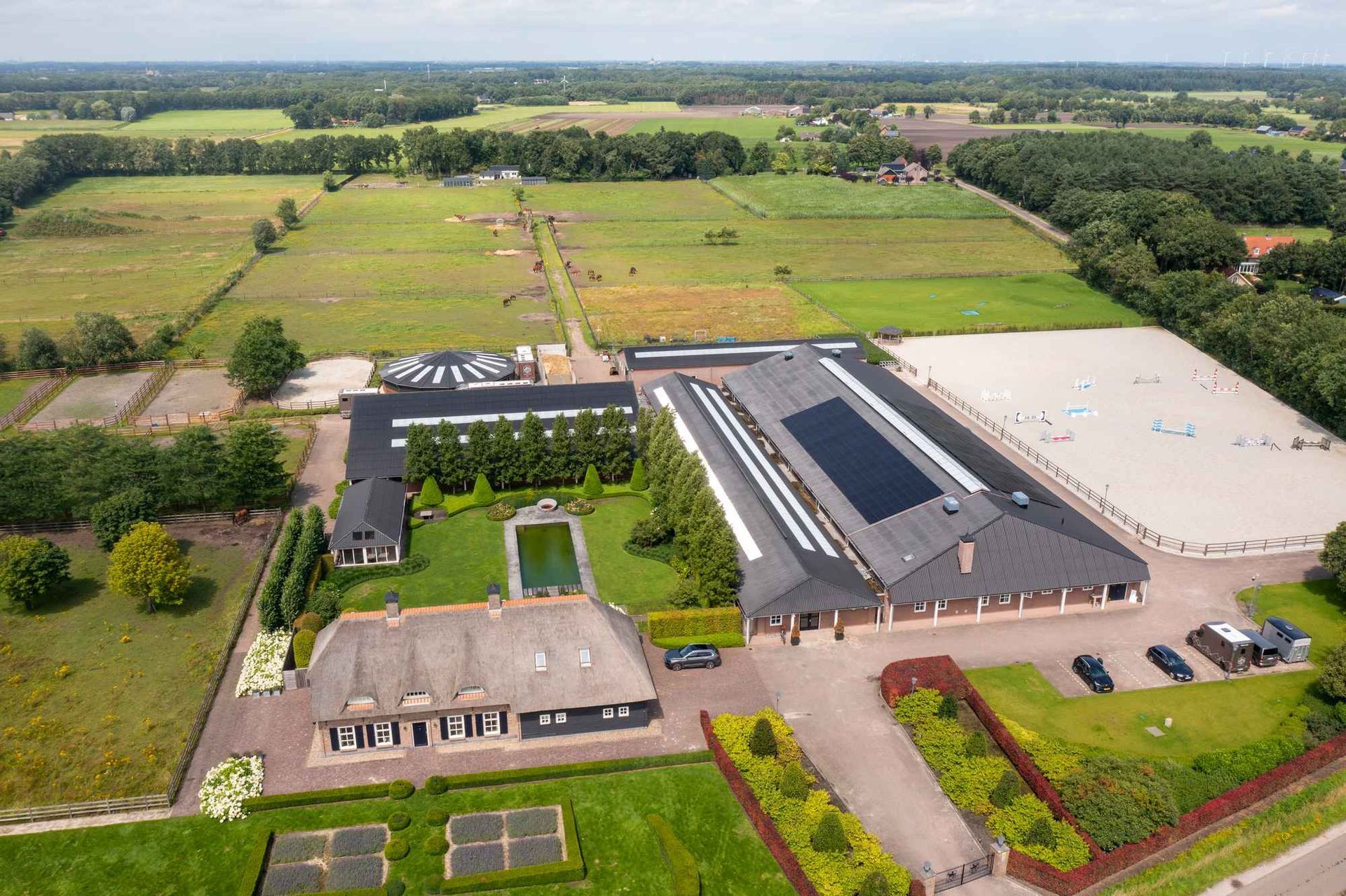 Een luchtfoto van een groot huis omgeven door velden en bomen.