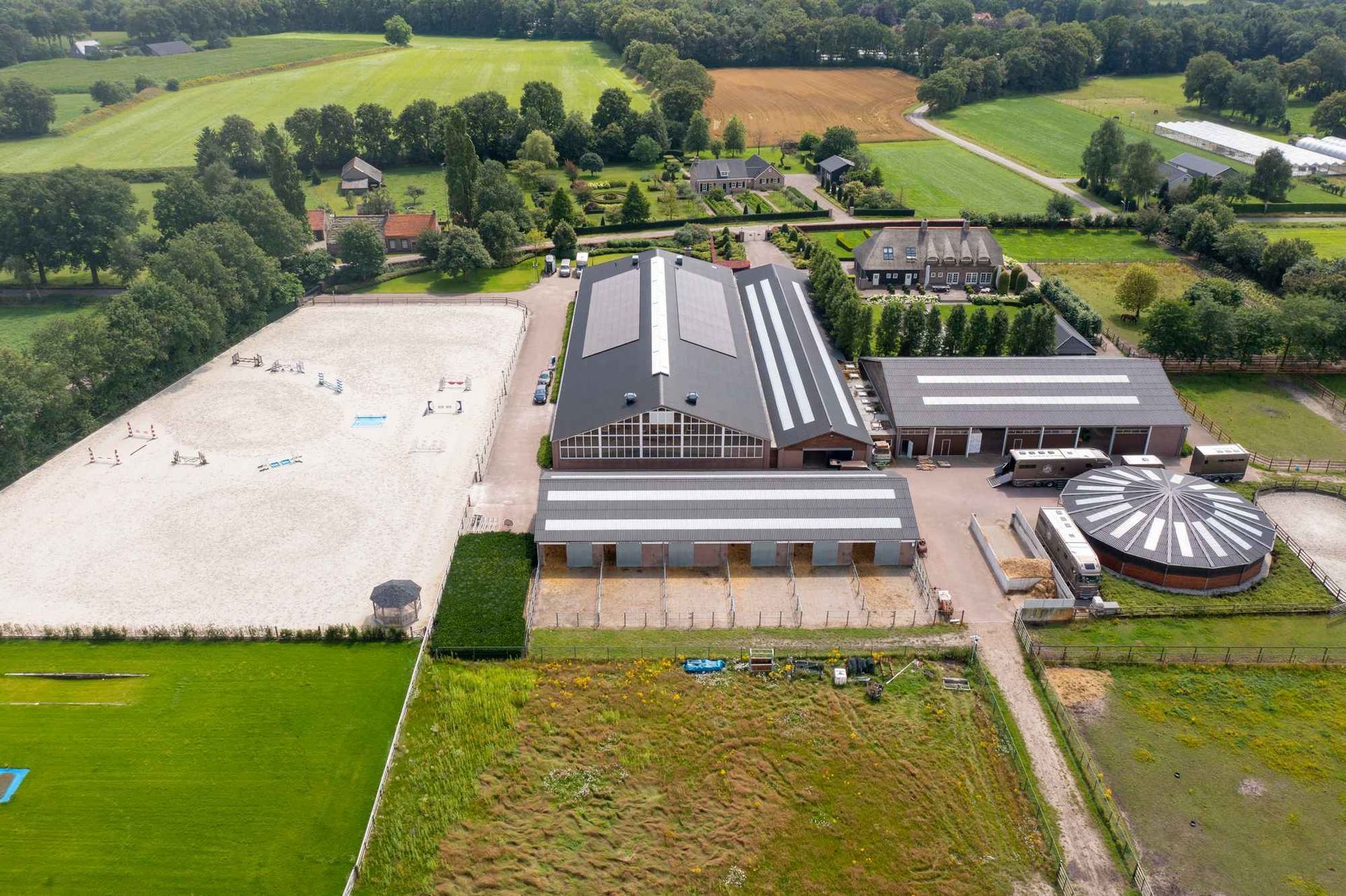 Een luchtfoto van een boerderij met een groot gebouw in het midden van een veld.