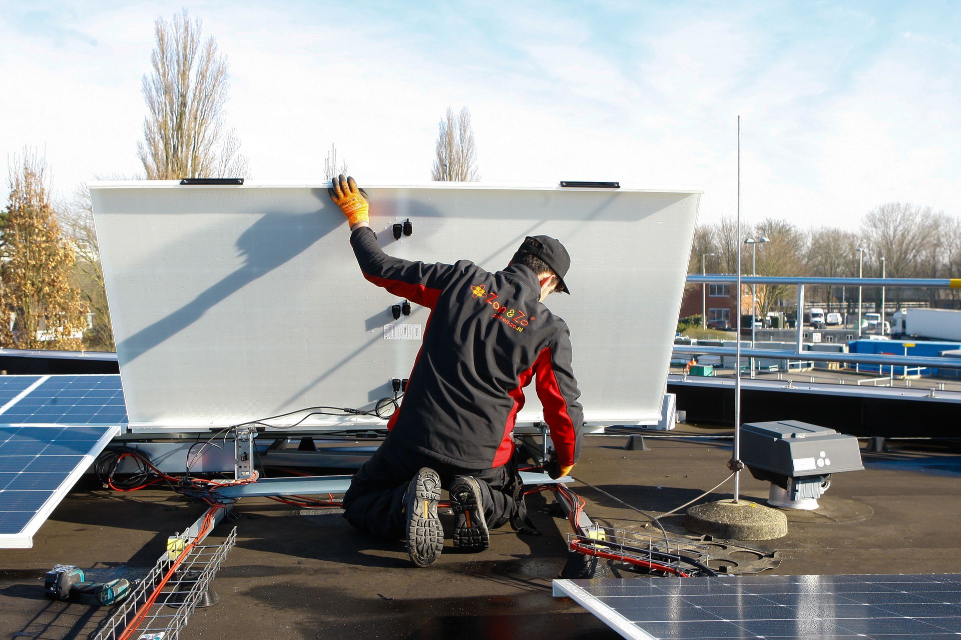 Een man installeert zonnepanelen op het dak van een gebouw.