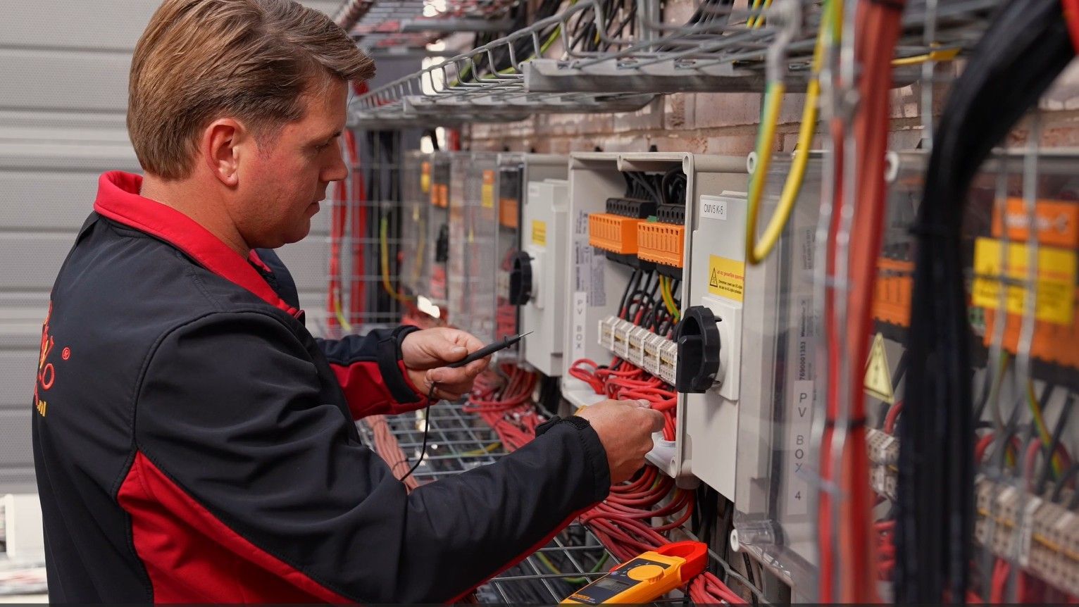 Een man werkt met een schroevendraaier aan een elektrische doos.