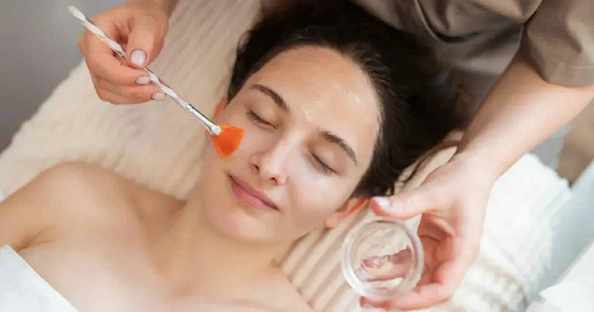 Facial treatment applied with a brush while a client relaxes on a spa bed