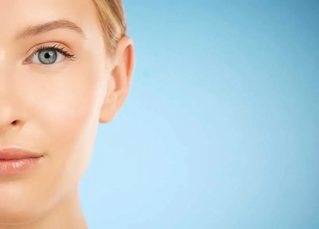 Close-up of a face with blue eye against a light blue background