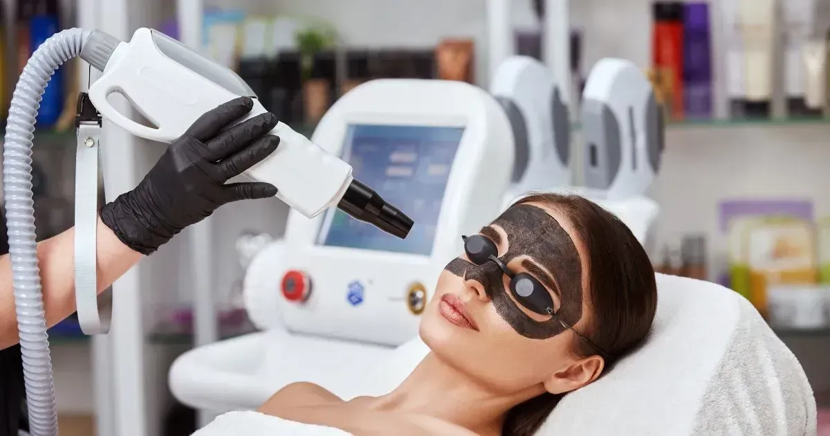 Spa treatment with masked client receiving a facial from a gloved technician in a bright salon