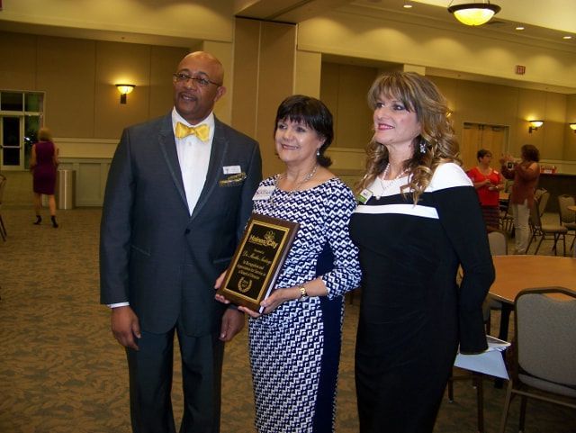 A man and two women are standing next to each other holding a plaque that says gmf