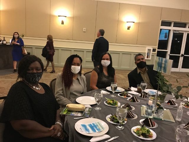 A group of people wearing face masks are sitting at a table.