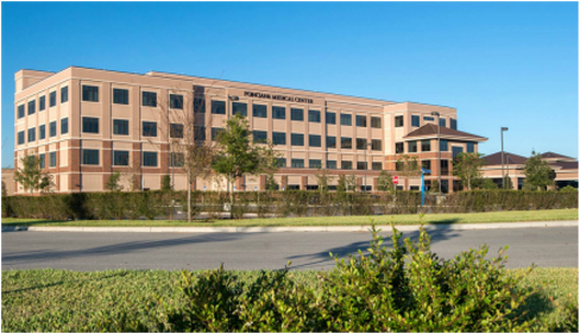 A large building with a lot of windows is sitting next to a road.