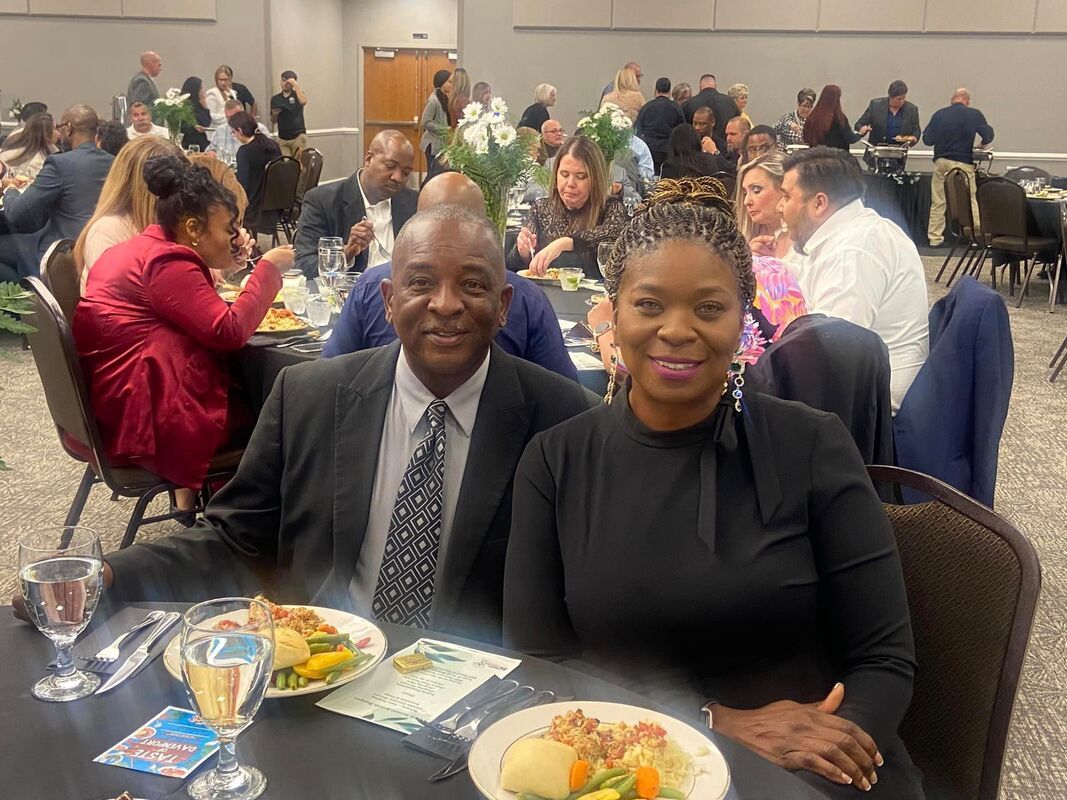 A man and a woman are sitting at a table with plates of food.