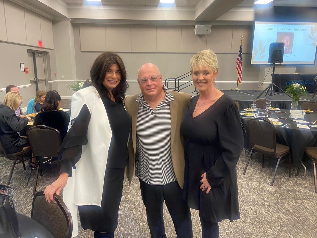A man and two women are posing for a picture in a room.