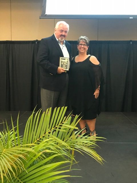 A man and a woman standing on a stage holding an award