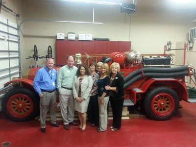 A group of people are standing in front of an old fire truck.