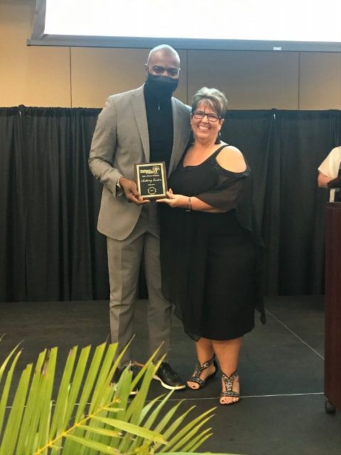 A man in a suit and a woman in a black dress holding an award
