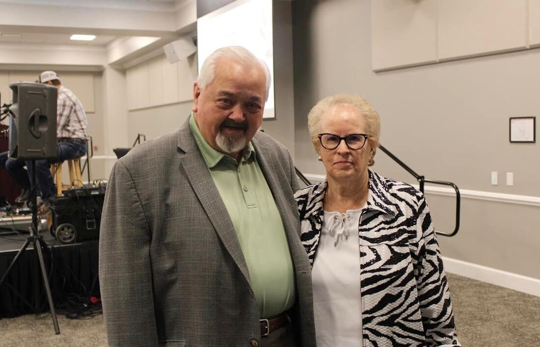 A man and a woman are posing for a picture in a room.