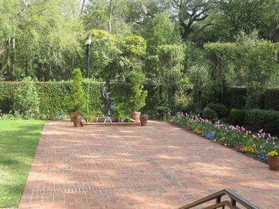 A brick driveway leading to a lush green garden