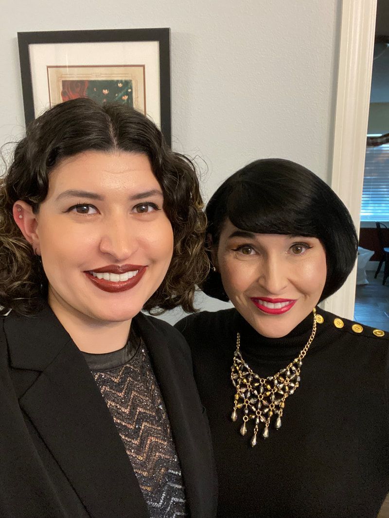 Two women are posing for a picture and one is wearing a gold necklace