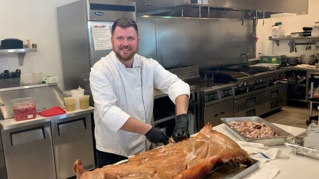 A chef is cutting a pig in a kitchen.