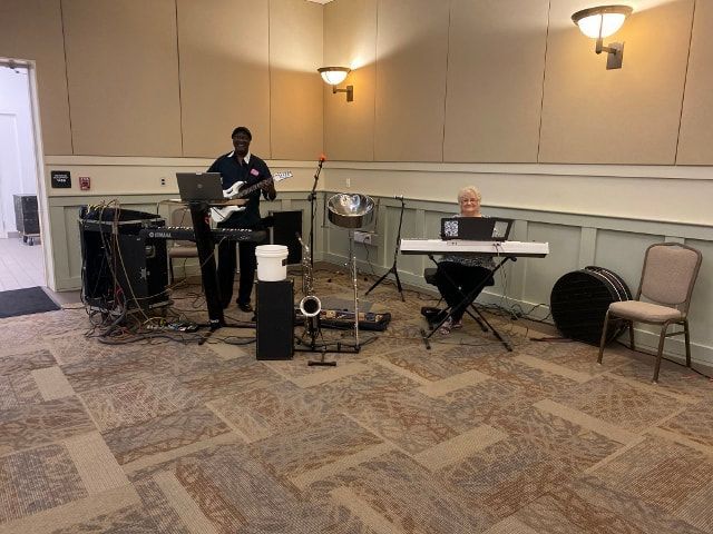 A man is playing a guitar and a man is playing a keyboard in a room.