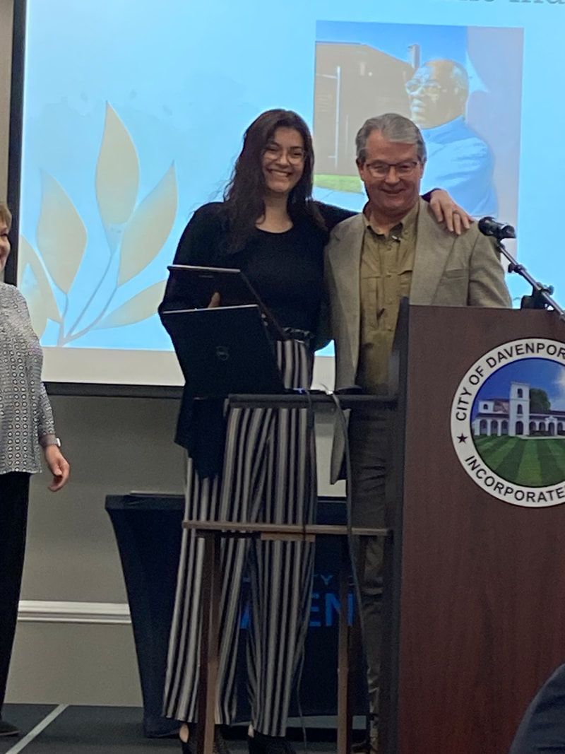 A man and a woman are standing in front of a podium with the city of galena logo on it.