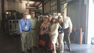 A group of people are posing for a picture in a warehouse.