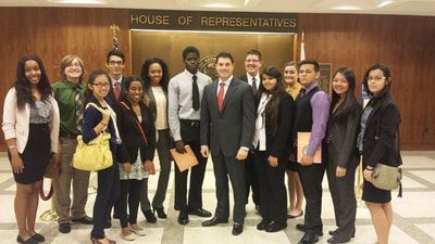 A group of people are posing for a picture in front of the house of representatives.
