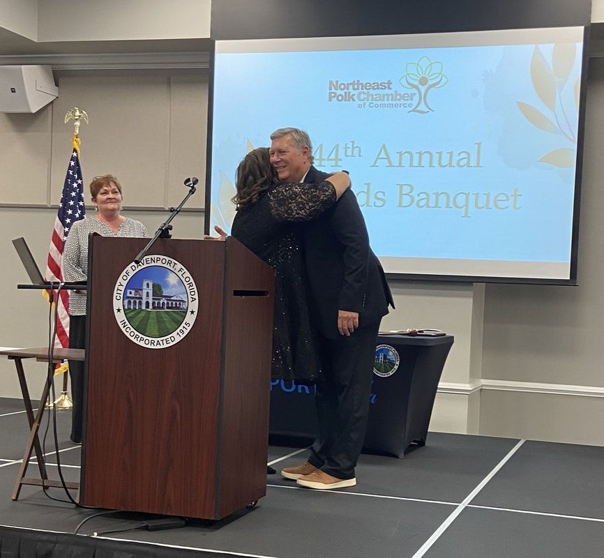 A man is hugging a woman behind a podium at the 44th annual awards banquet