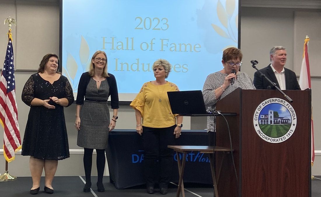 A group of women are standing in front of a podium at a hall of fame ceremony.