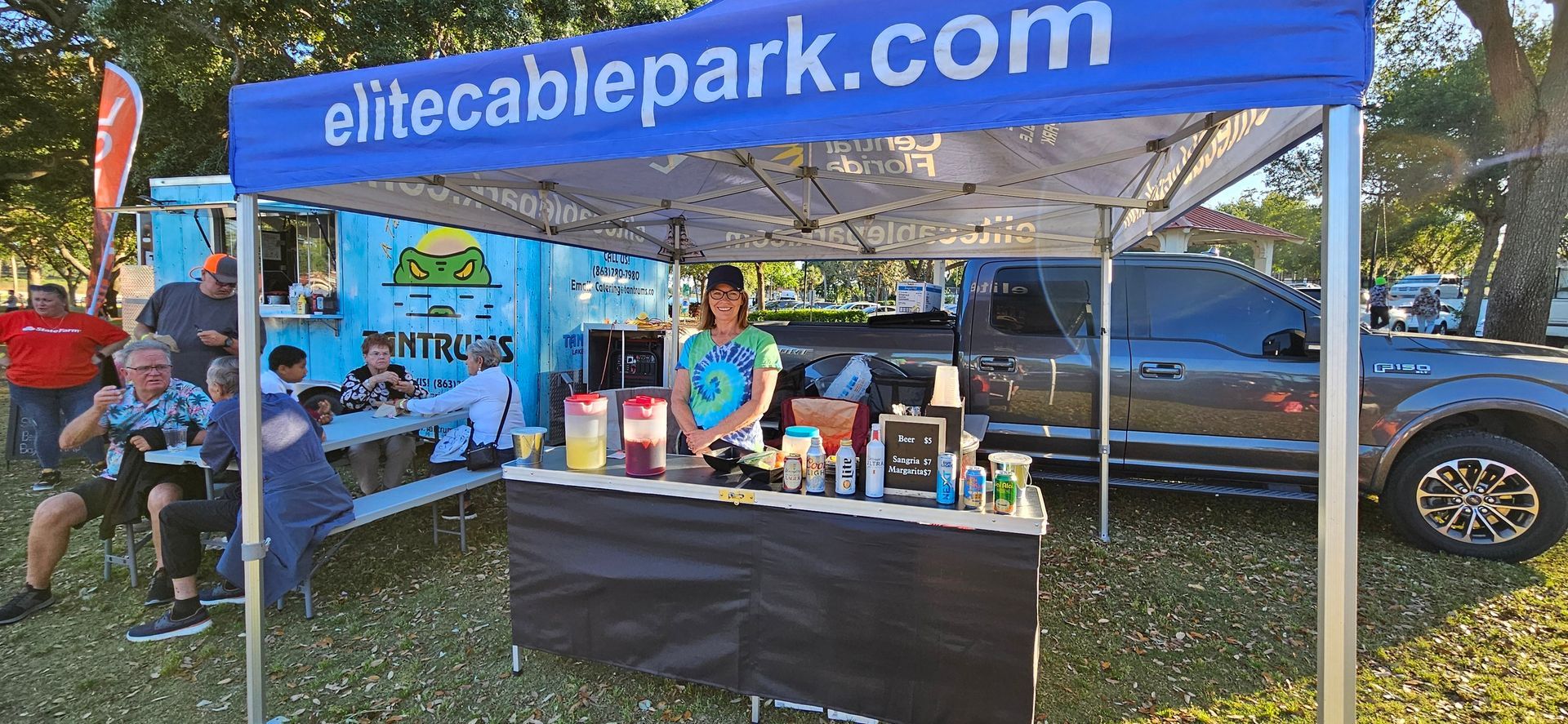 A woman is standing behind a table under a blue tent.