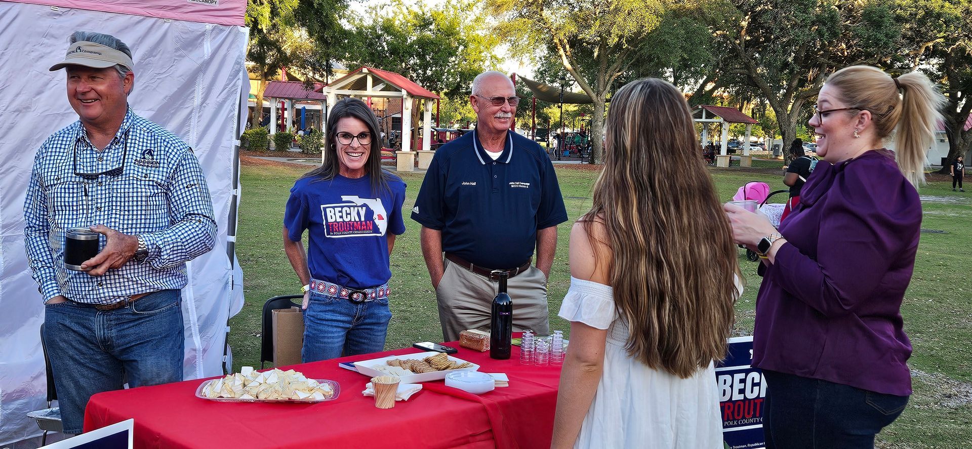 A group of people are standing around a table in a park.