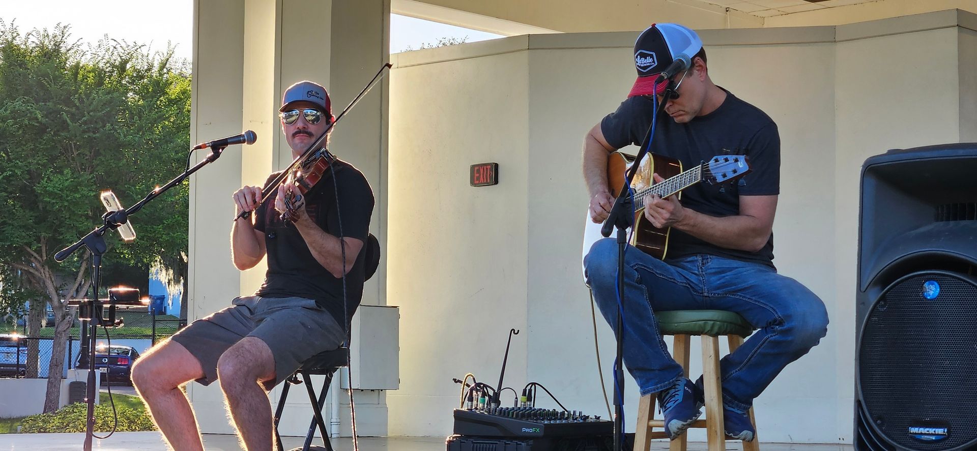 Two men are playing violins and guitars on a stage.