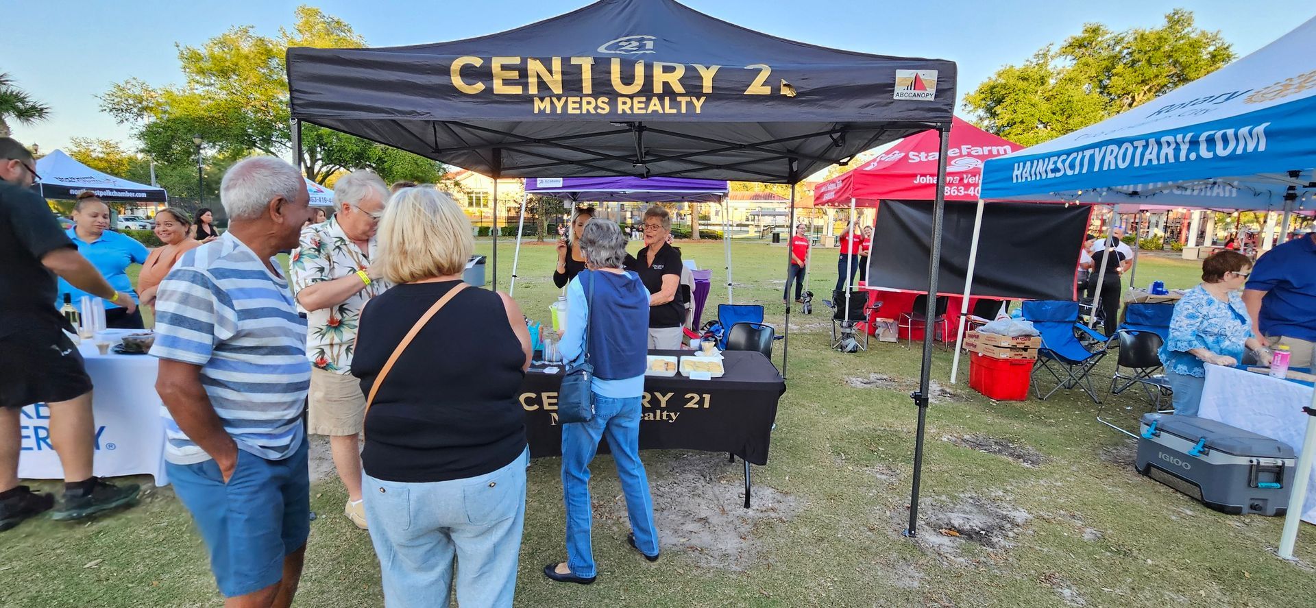 A group of people are standing in front of a century 2 tent.
