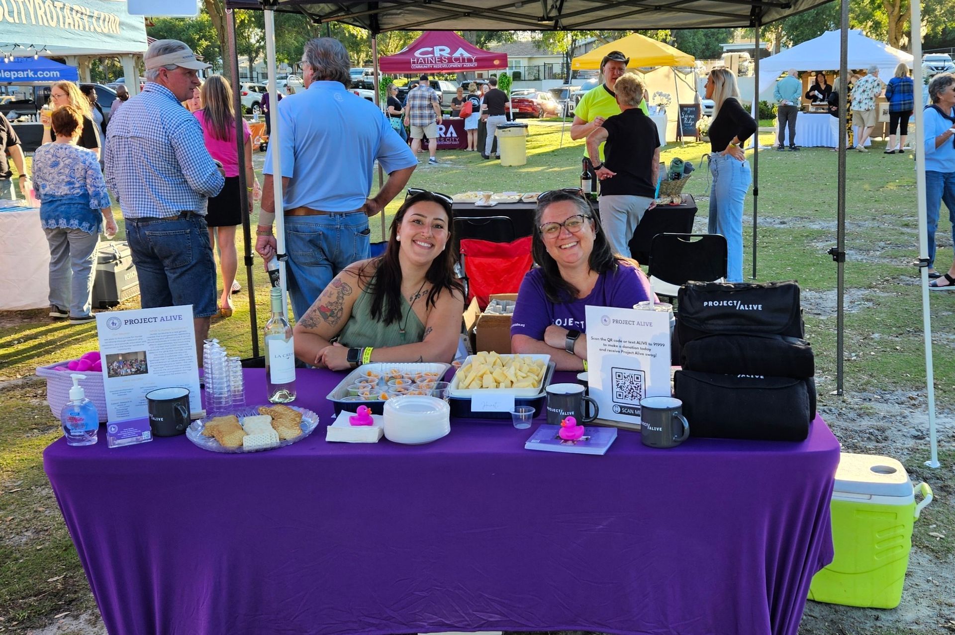 Two women are sitting at a table with a purple table cloth.