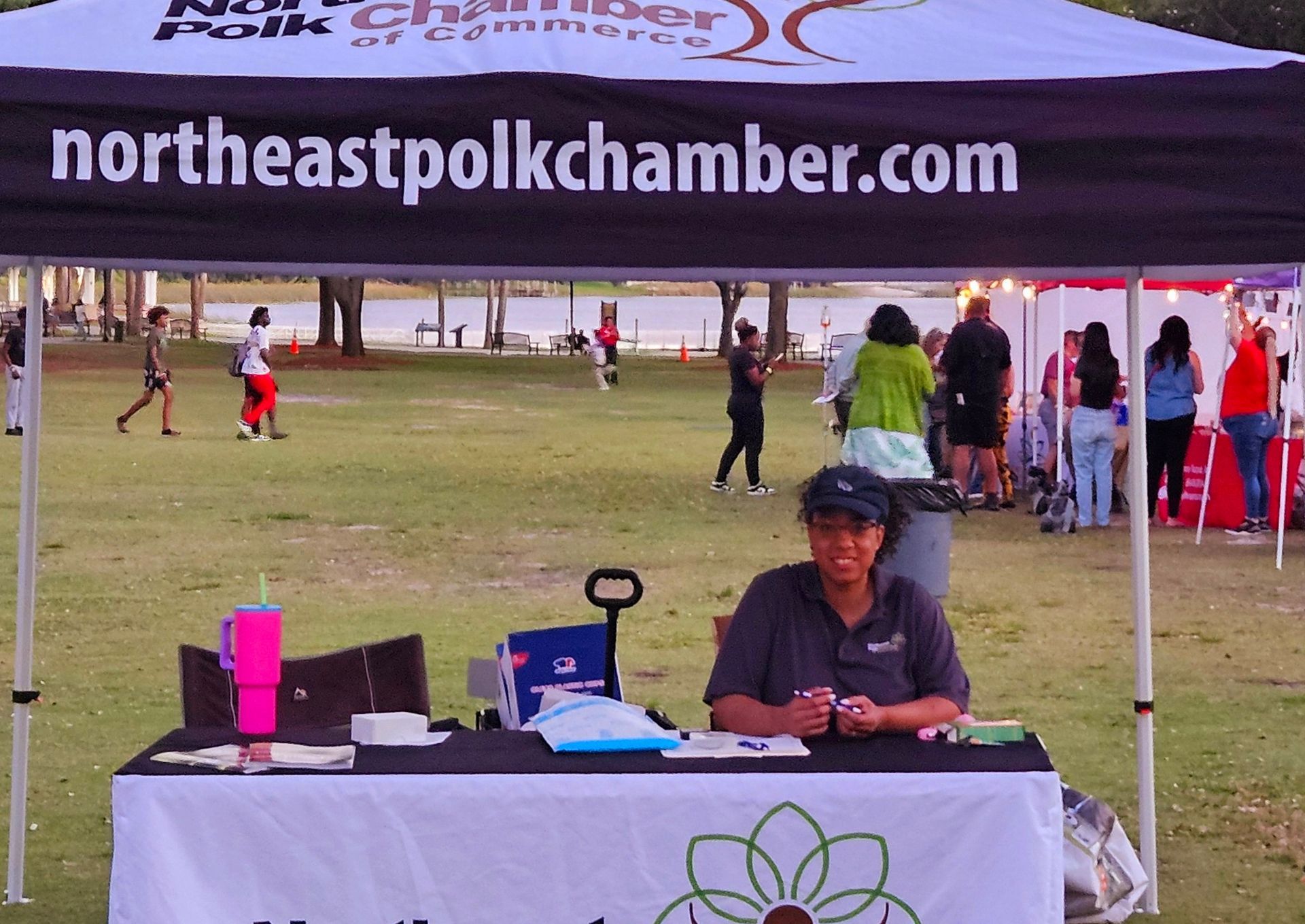 A woman sits at a table under a northeastpolkchamber.com tent