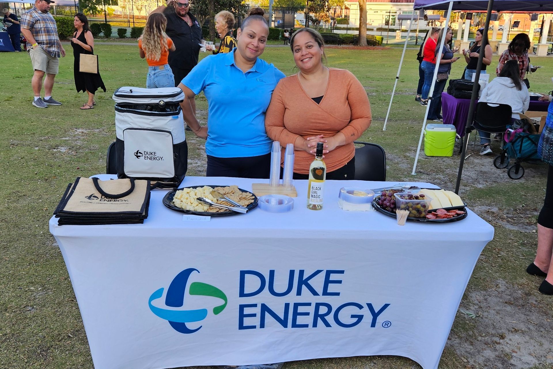 Two women are standing behind a table with duke energy written on it.