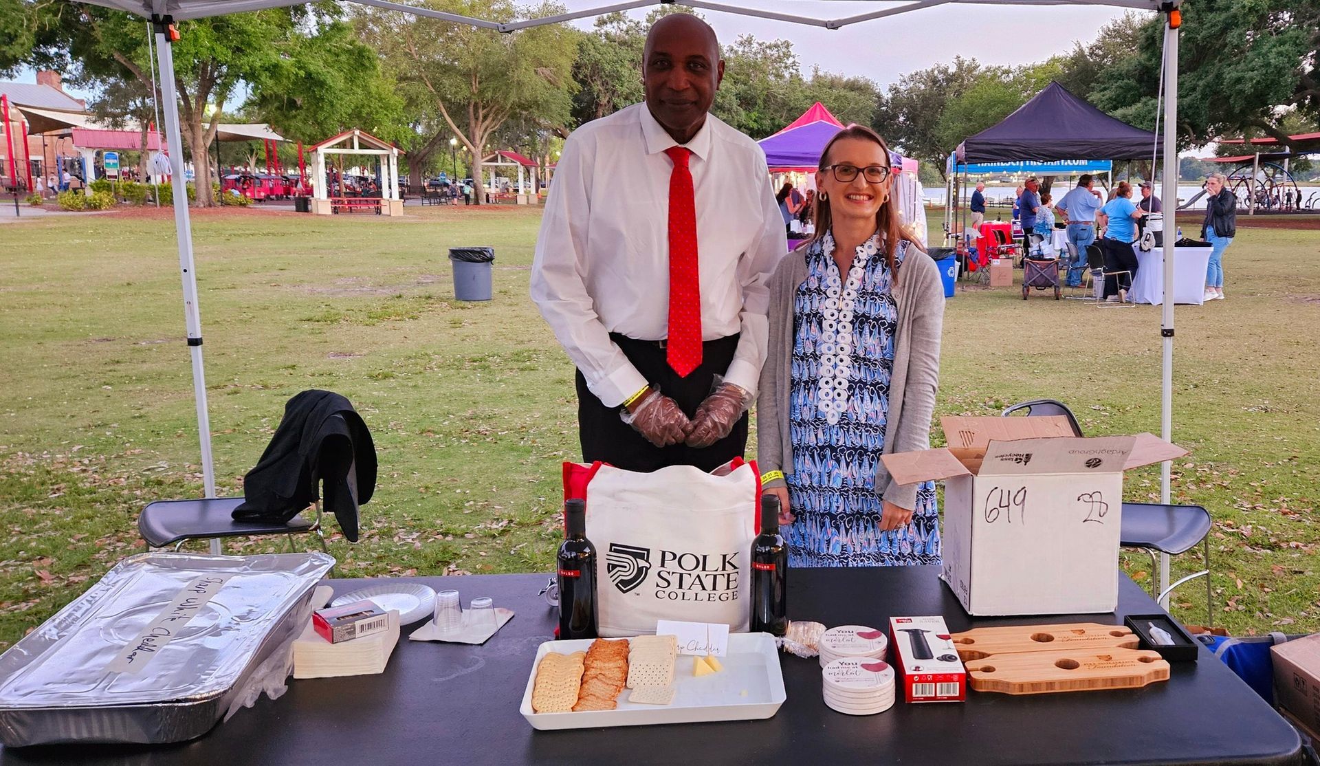 A man and a woman are standing in front of a table with food on it.
