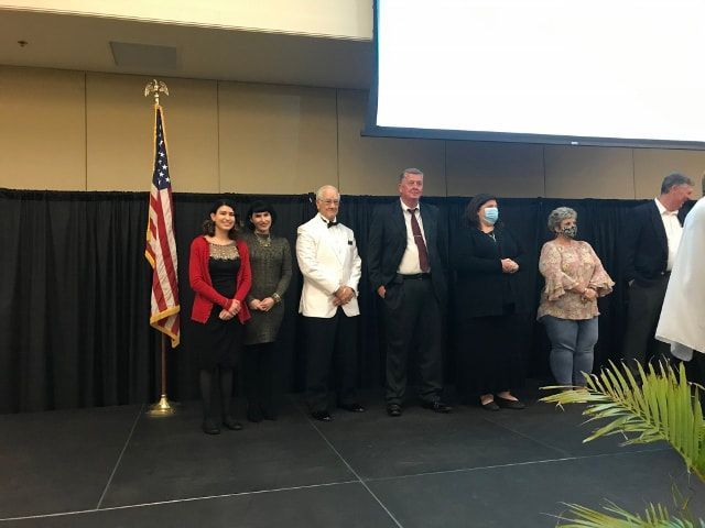 A group of people standing on a stage in front of an american flag
