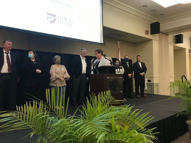 A group of people are standing on a stage in front of a podium.