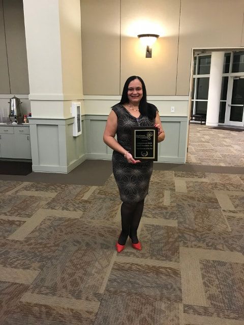 A woman is standing in a room holding a plaque.
