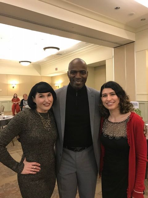 A man and two women are posing for a picture in a room.