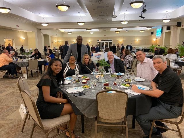 A group of people are sitting at tables in a large room.
