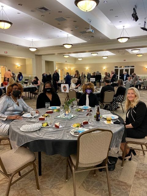 A group of people are sitting at tables in a large room.