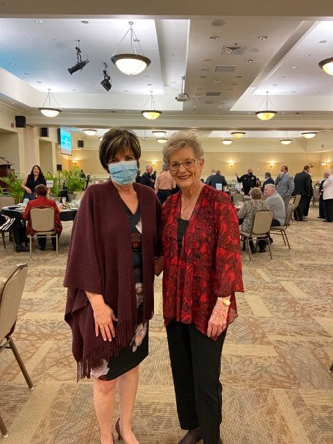 Two women wearing masks are standing next to each other in a room.