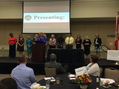 A group of people standing in front of a screen that says presenting