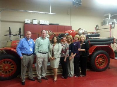 A group of people standing in front of an old fire truck.