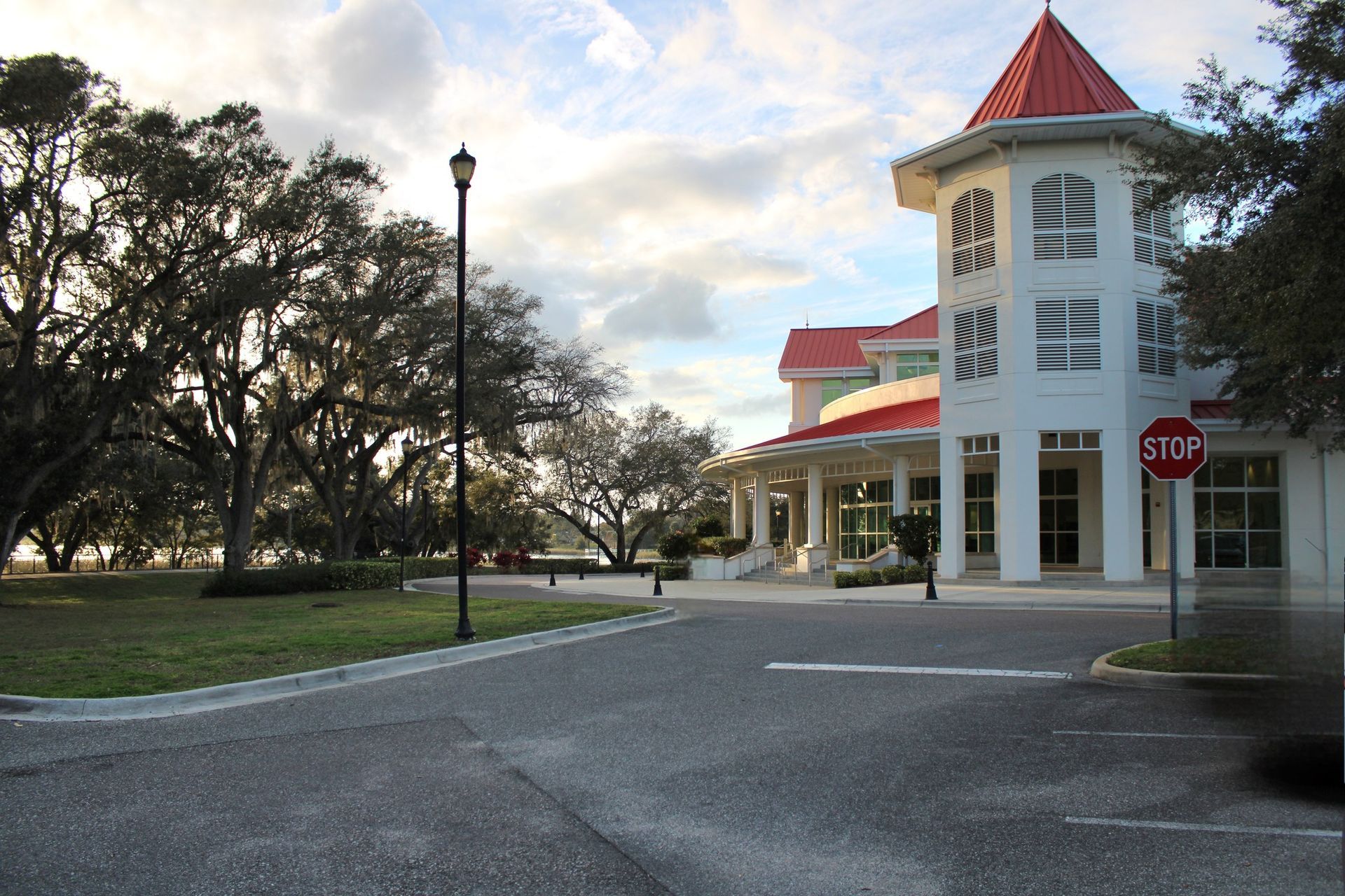 A large white building with a red roof and a stop sign in front of it