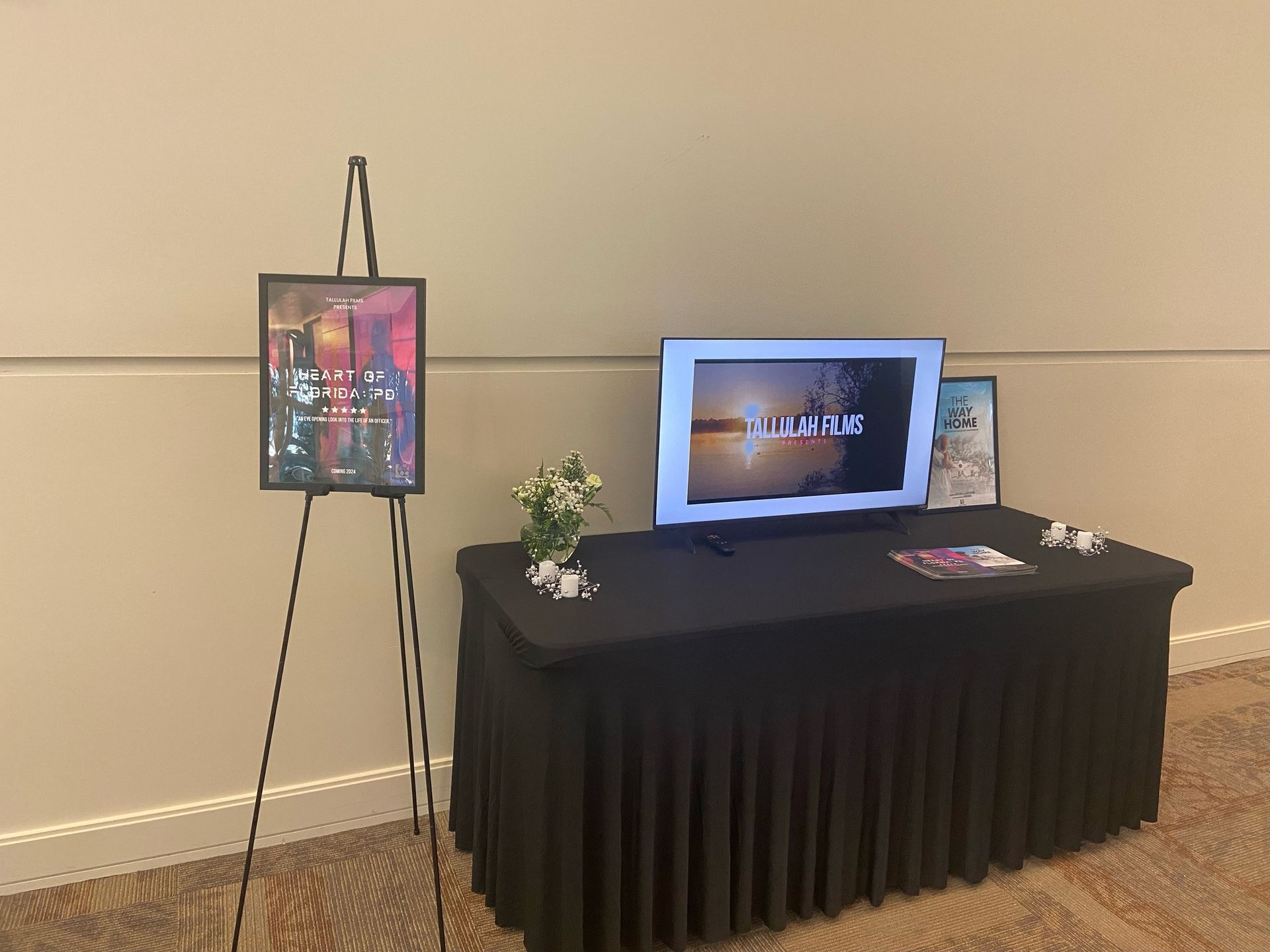 A table with a tv and paintings on it in a room.
